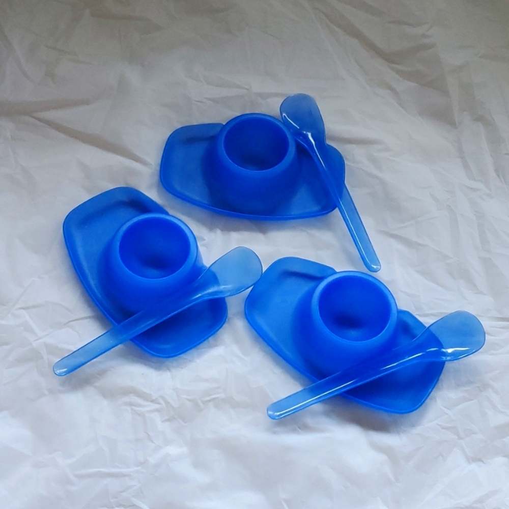 Egg cups saucers in blue with matching spoons.